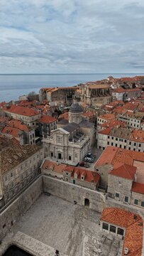 Aerial view of Dubrovnik Old Town and its medieval city walls. Cinematic shot of the UNESCO World Heritage site featuring limestone streets and terracotta roofs in Croatia.