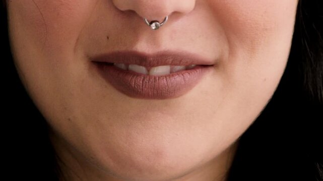 Mouth, closeup and woman with smile for nose ring, skin and pride with metal bar for style expression. Person, steel jewelry and beauty with septum piercing, gemstone or lipstick with body art