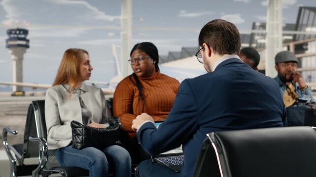 Impatient women in airport checking plane departure time on boarding pass, being late. Multiethnic passengers enduring tedious waiting for delayed flights to resume, checking timetable online