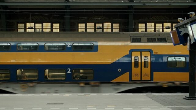 Double decker intercity train arriving at the platform in Amsterdam Centraal station at dusk