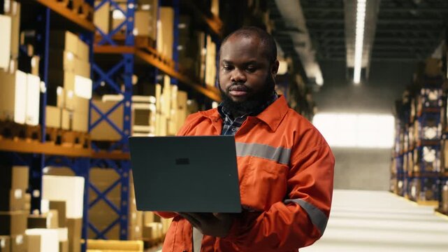Portrait of black worker preparing freight shipment in industrial depot, supply chain management coordinates import export delivery and parcel tracking. Transportation operations with safety.