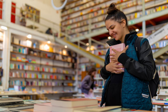 Young woman finding joy hugging favorite book in bookstore