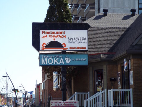 Gatineau, Quebec, Canada &ndash; April 18, 2026: A signs for "Restaurant La Teranga and Salon de coiffure Moka" stand outside a brick building in Gatineau at 303 Boulevard Saint-Joseph.