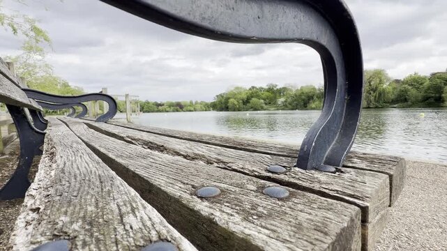 Wooden park bench beside calm lake panning