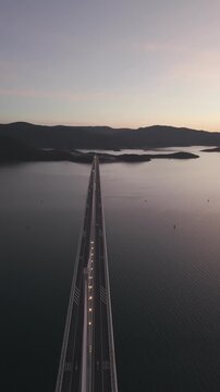 High-angle perspective of Peljesac Bridge over the Adriatic Sea during twilight. Professional drone photography of Croatia's landmark infrastructure at golden hour.
