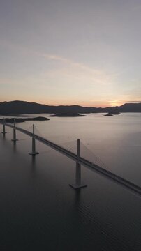 High-angle perspective of Peljesac Bridge over the Adriatic Sea during twilight. Professional drone photography of Croatia's landmark infrastructure at golden hour.