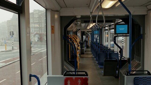 Interior of a moving and empty tram with views of the city streets of Amsterdam on a foggy day