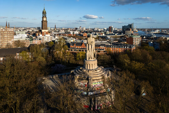 Aerial view of the Bismarck Monument with peace graffiti surrounded by lush trees with the St. Michael's Church and Elbphilharmonie in the background in Hamburg, Hamburg, Germany.