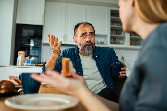 Middle-aged couple arguing over breakfast in a home kitchen