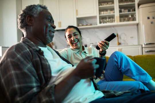 Caregiver and senior man watching tv at home