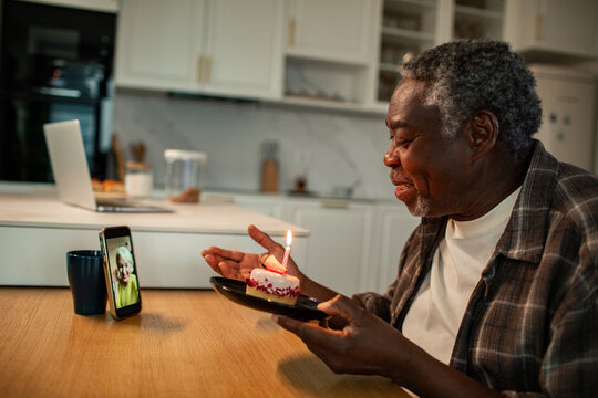 Senior man celebrating birthday on video call in home kitchen