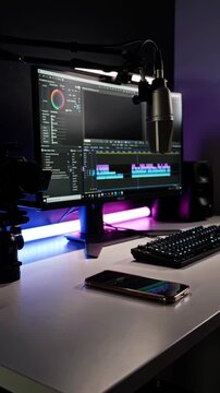 Content creator desk at night with RGB lighting, microphone and video editing on PC, colorful streaming setup pan shot 4K