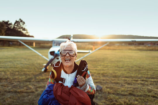Smiling senior skydiver on airfield at sunset