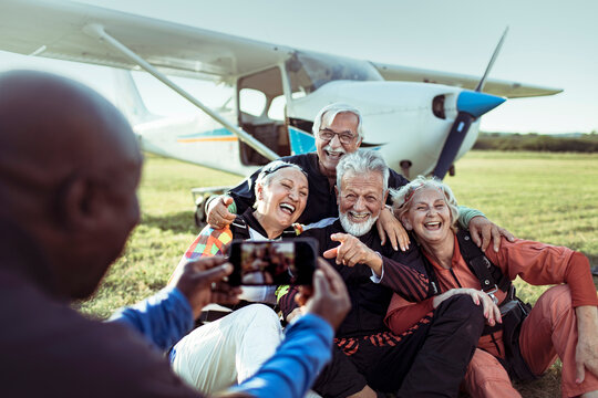 Senior friends posing for photo after skydiving at airfield