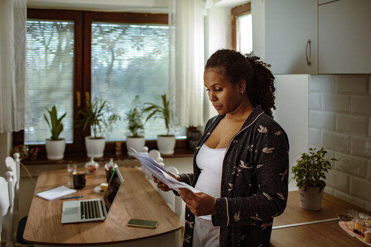 Woman reviewing household bills in home kitchen