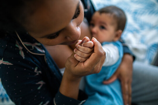 Mother kissing baby's hand at home