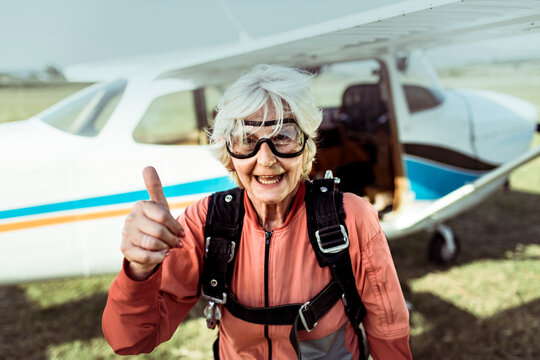 Senior woman skydiver giving thumbs up at airfield