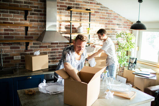 Two men packing kitchen boxes in new home
