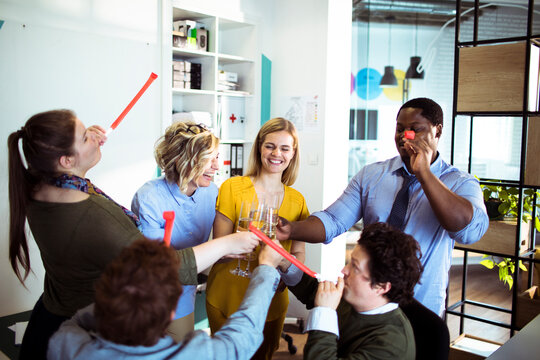 Coworkers toasting success during celebration in modern office