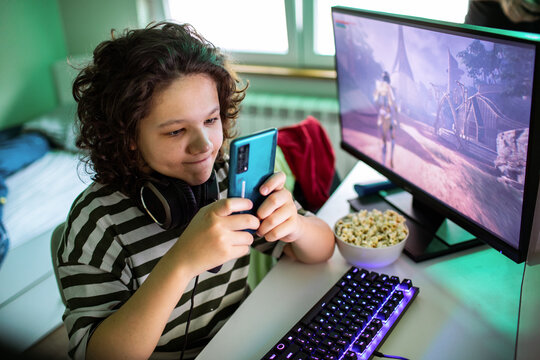Teen gamer playing a mobile game at home desk