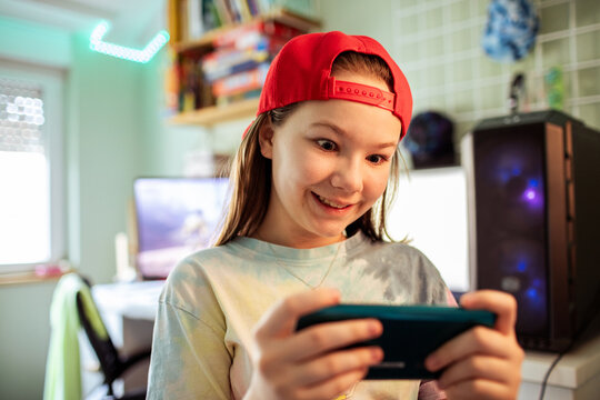 Smiling tween girl gaming on smartphone at home