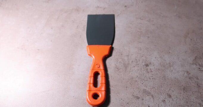 Handyman with putty knife at grey table closeup