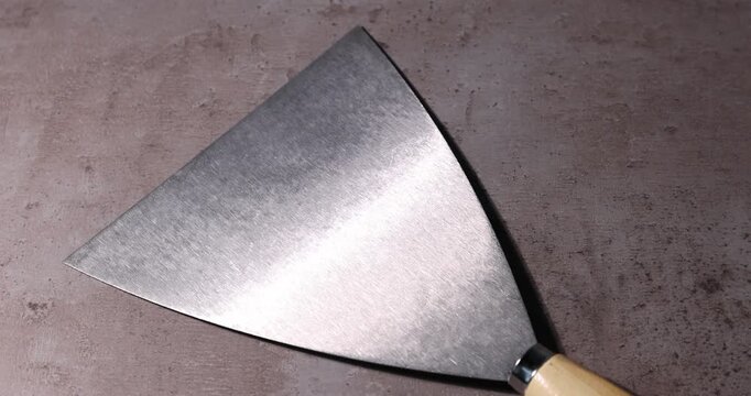 Putty knife on grey table, closeup. Construction tool
