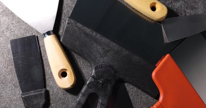 Putty knives on grey table, spinning. Top view