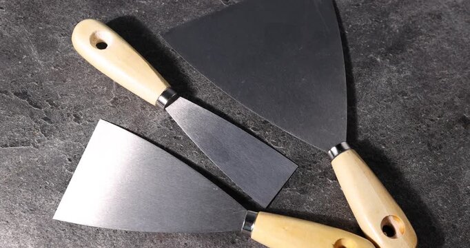 Putty knives on grey table, closeup. Construction tool