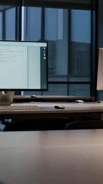 Empty office at night with multiple monitors, slow pan shot, dark corporate workspace with illuminated screens 4K