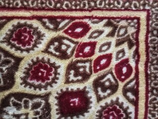 Traditional Ornamental Carpet Close Up Texture.  Traditional patterned carpet featuring intricate floral and geometric motifs in rich red, cream, beige, and brown tones with soft textured woven fabric © Shuttereyes7