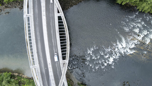 Aerial view of the modern Ponte do Milenio bridge with a white van driving over the flowing river and rapids in Orense, Ourense, Spain.
