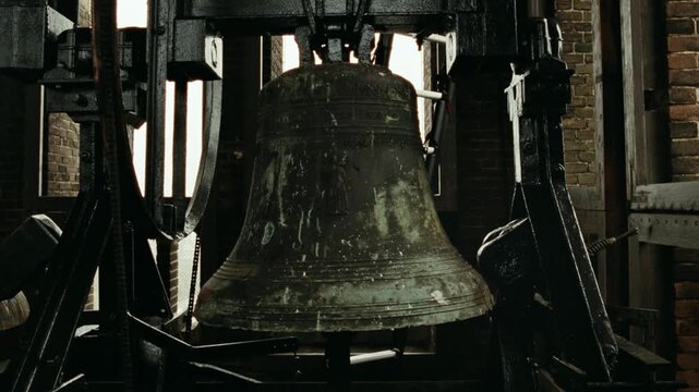 Large antique bronze bell ringing inside a historic church tower in Amsterdam, Netherlands