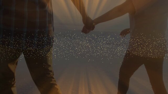 Couple entering frame walking toward horizon, sparkles aligning with joined hands for sunset travel