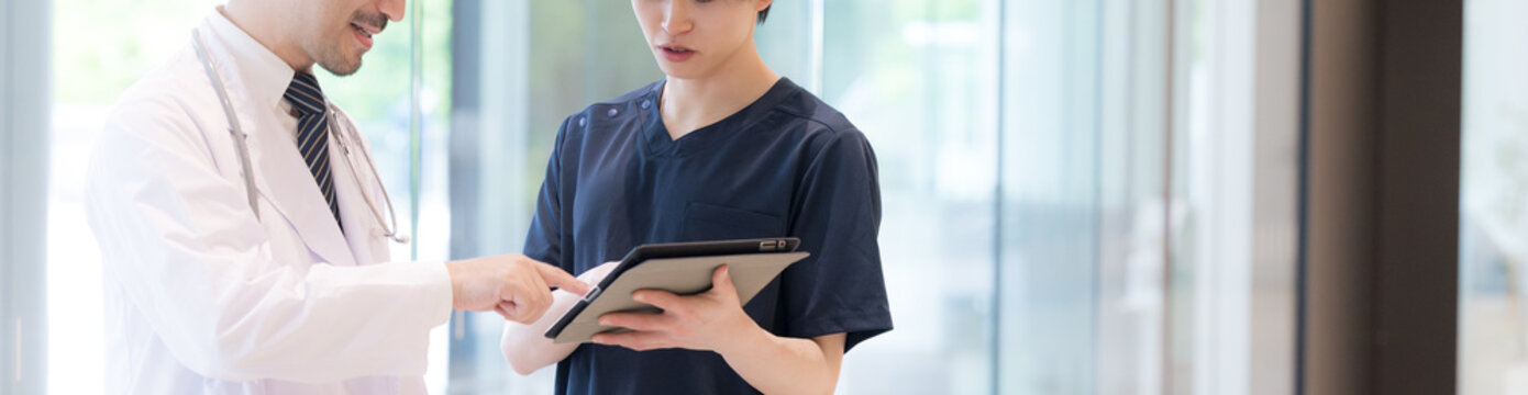タブレットを見ながら指導や申し送りする医師と新人ドクターや看護師医療現場のDXとチーム連携イメージバナー