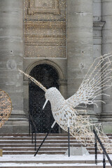 Fototapeta premium MONTREAL, CANADA, 23 December 2025 : Hummingbird sculpture winter snow urban art installation building lights