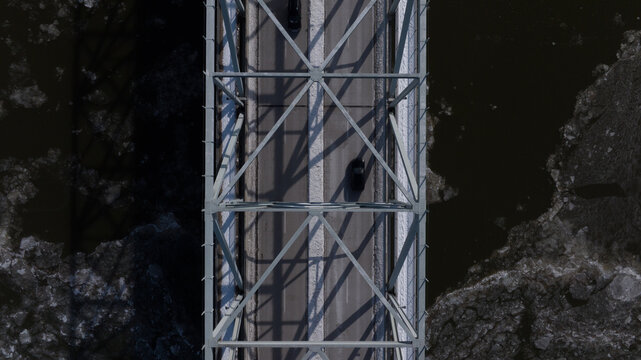 Aerial view of a steel truss bridge crossing a river filled with ice floes and cars driving on the road Cincinnati, Ohio, United States.