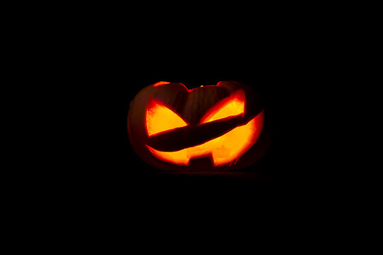 Rostro de calabaza de Halloween brillante aislado en fondo negro.