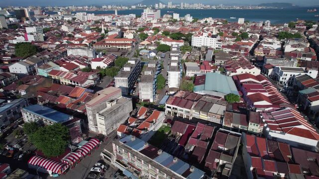 Drone footage highlighting the dense cityscape of Penang&rsquo;s Georgetown district with tightly packed buildings and waterfront backdrop.