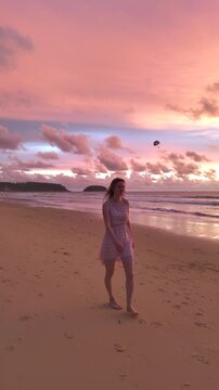 Young Woman In Summer Dress Walking On Sandy Karon Beach In Phuket, Thailand At Sunset. vertical shot