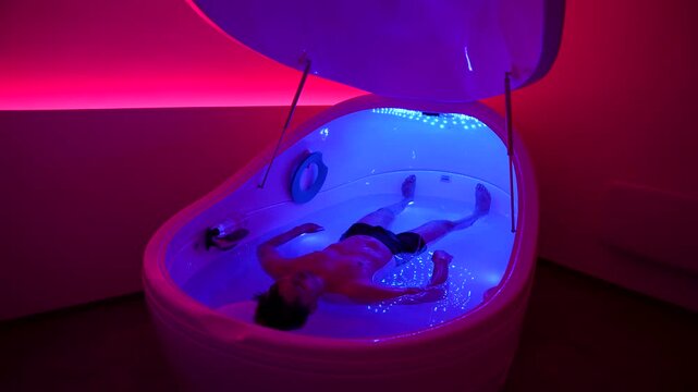 Timelapse of a young man floating in a saline therapy pod, ideal for wellness, relaxation, spa, recovery, mindfulness, sleep, stress relief, and calm lifestyle concepts