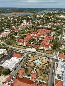 Aerial view of Flagler College featuring red-tiled roofs and Spanish Renaissance architecture with lush courtyards and palm trees in St. Augustine, Florida, United States.