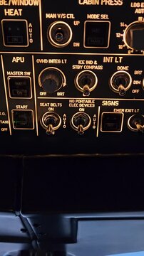 Vertical close-up of a pilot activating the no electronic devices sign on an overhead cockpit panel. Professional aviation safety procedure during a flight