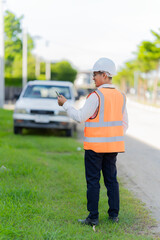Obraz premium A male civil engineer or construction supervisor, wearing a yellow safety helmet and reflective vest, is on a construction site, representing a real estate development concept for a housing constructi