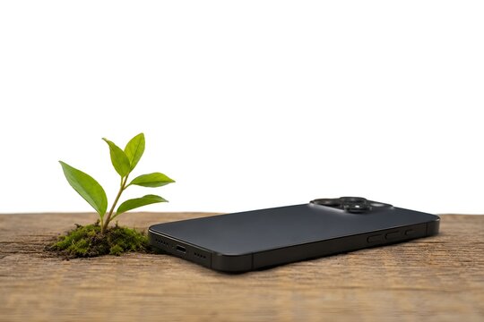 Sustainable technology and green electronics concept. A small plant grows beside a modern smartphone to represent eco friendly innovation. Smartphone on wood