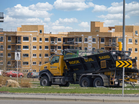 Calgary, Alberta, Canada. May 12, 2026. A yellow Blackstone slinger truck parked near a multi-story residential building under construction.