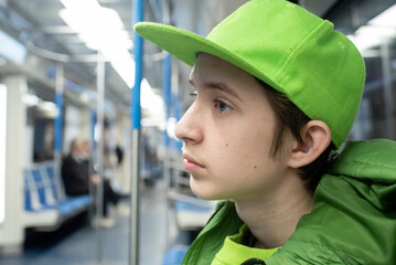 Profile portrait of a teenage boy in bright green cap riding subway train © Ruslan Russland