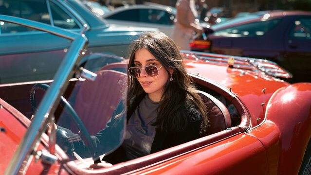 Berlin, Germany - May 2, 2026. Woman in red MG roadster at car show
