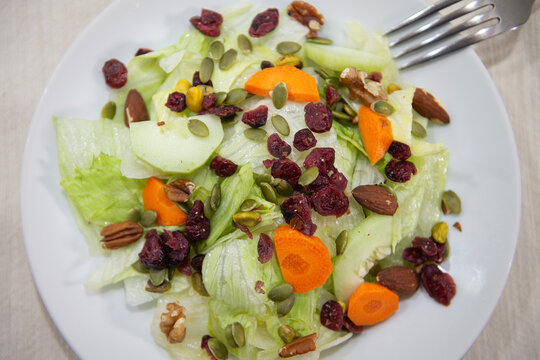 Ensalada con lechuga, pepino zanahoria, granos y semillas, sobre una mesa, vista cenital con tenedor en el fondo comida y estilo de vida