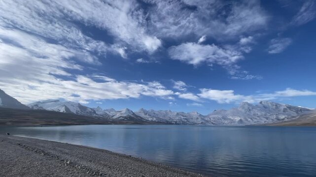 A 40 second continuous long take of majestic snow covered mountain peaks reflecting beautifully on a pristine plateau lake.
